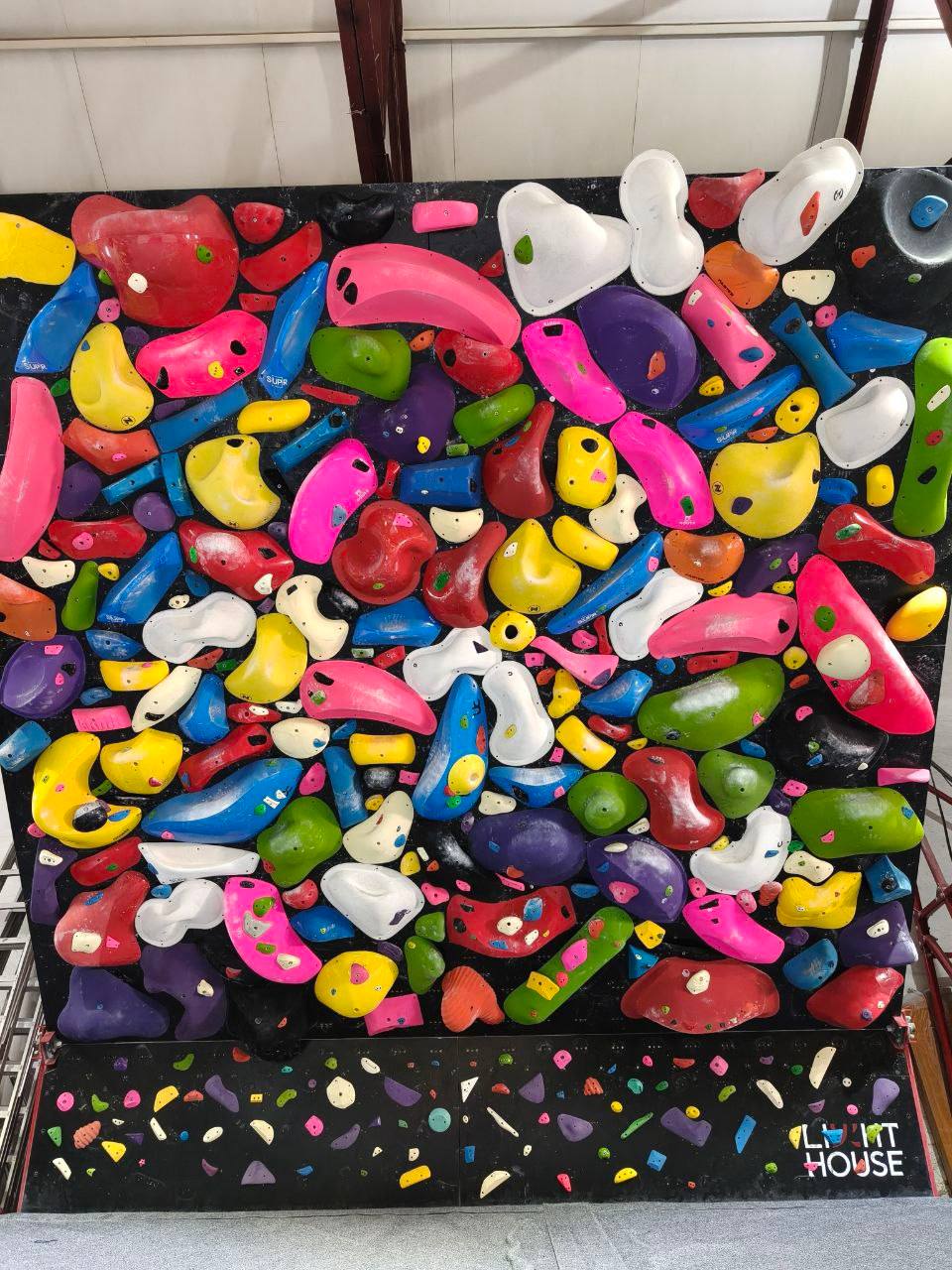 A colourful indoor spray wall filled with climbing holds